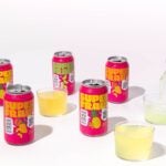 An arm with light skin tone pours Superfrau sparkling beverages from a can into cups.