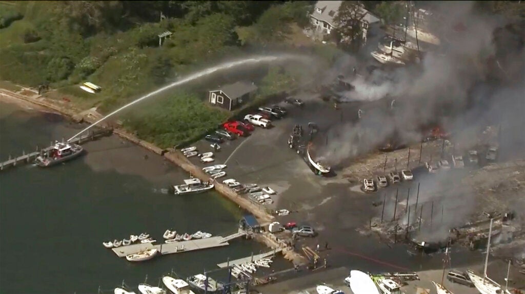 A large fire consumes boats, buildings and vehicles at the shipyard