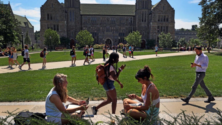 Boston College students sit on a wall at the BC campus.