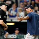 Alex Cora and umpire Bill Welke argue, with Cora's arms out, exasperated.