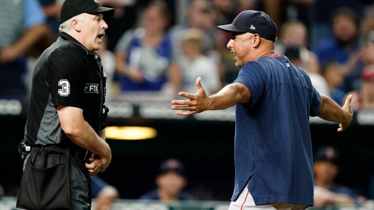 Alex Cora and umpire Bill Welke argue, with Cora's arms out, exasperated.
