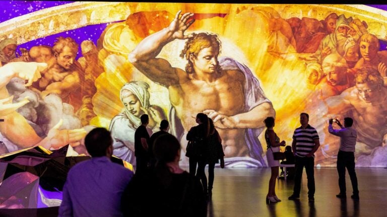 Crowds observe "The Last Judgement" by Michelangelo at "Immersive Vatican."