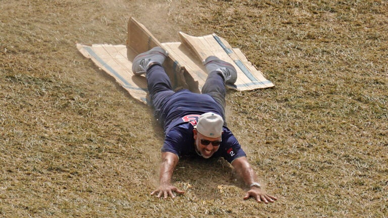 Alex Cora smiles as he slides headfirst down a hill on a piece of cardboard.