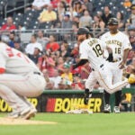 Josh Winckowski crouches as Pittsburgh's Ben Gamel rounds first base in the background.
