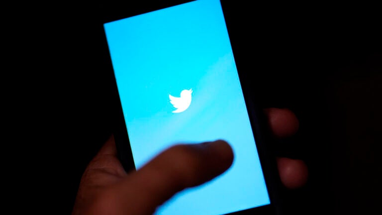 alt = blue and white Twitter logo on phone screen