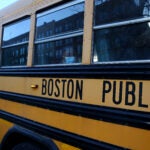 A Boston Latin Academy student waits on her school bus after attending her school day.