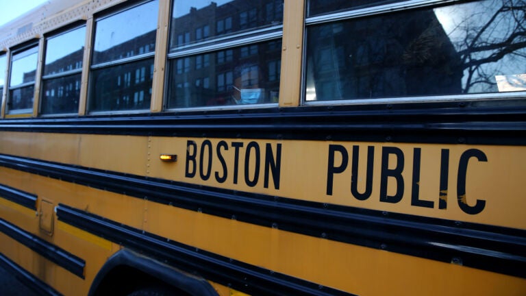 A Boston Latin Academy student waits on her school bus after attending her school day.