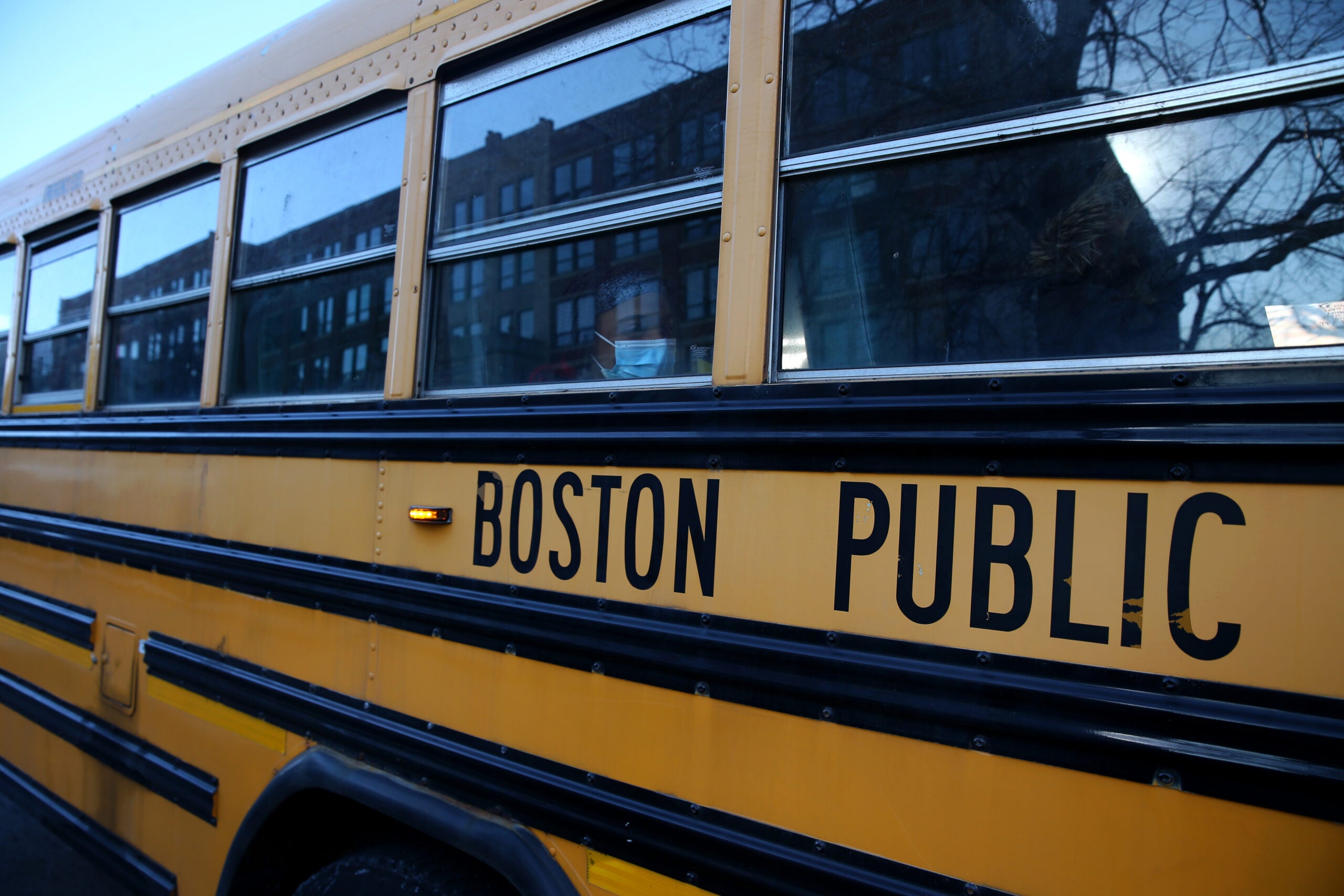 A Boston Latin Academy student waits on her school bus after attending her school day.