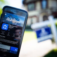 picture of cellphone with zillow ap in front of home for sale