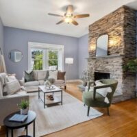 a grayish-blue living room with a stone fireplace and wood flooring.