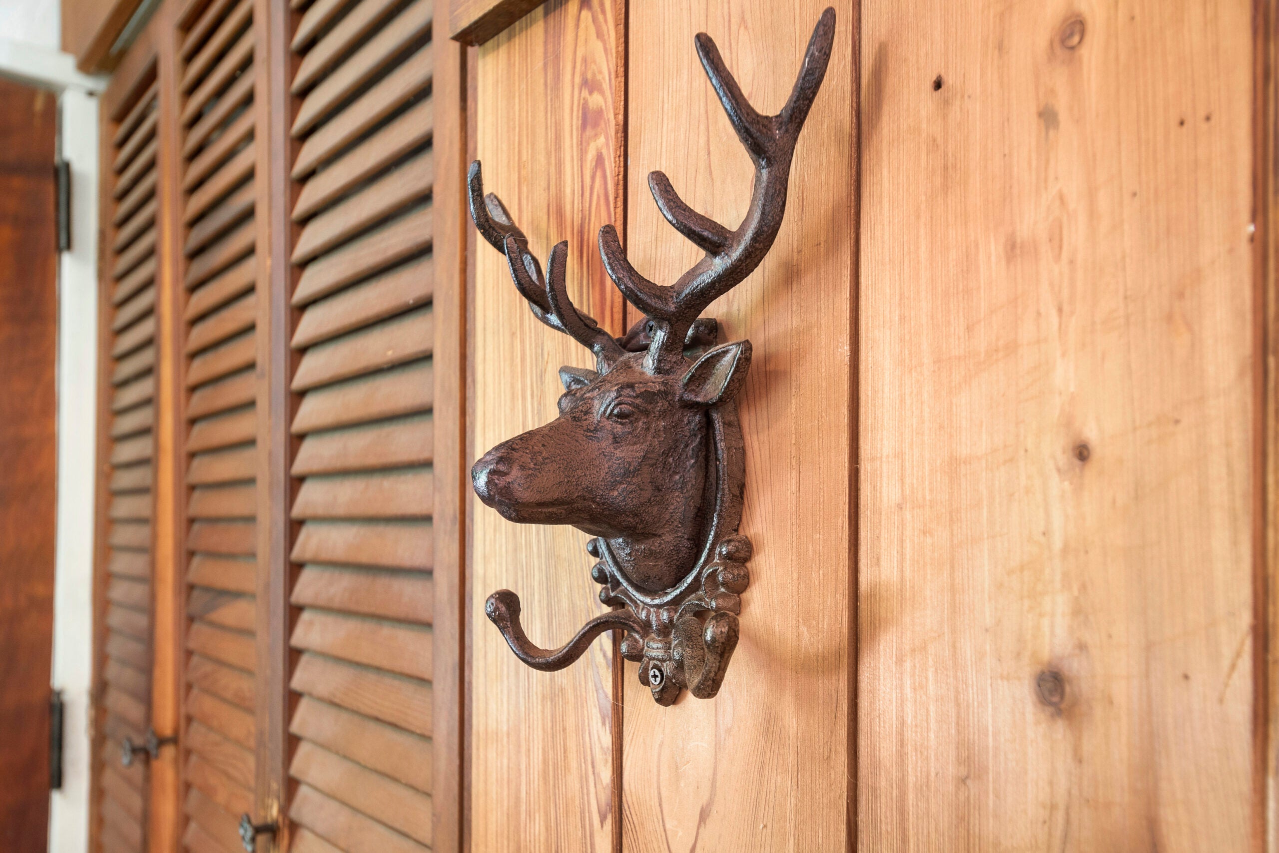 An iron rack shaped like a deer on a wood wall.