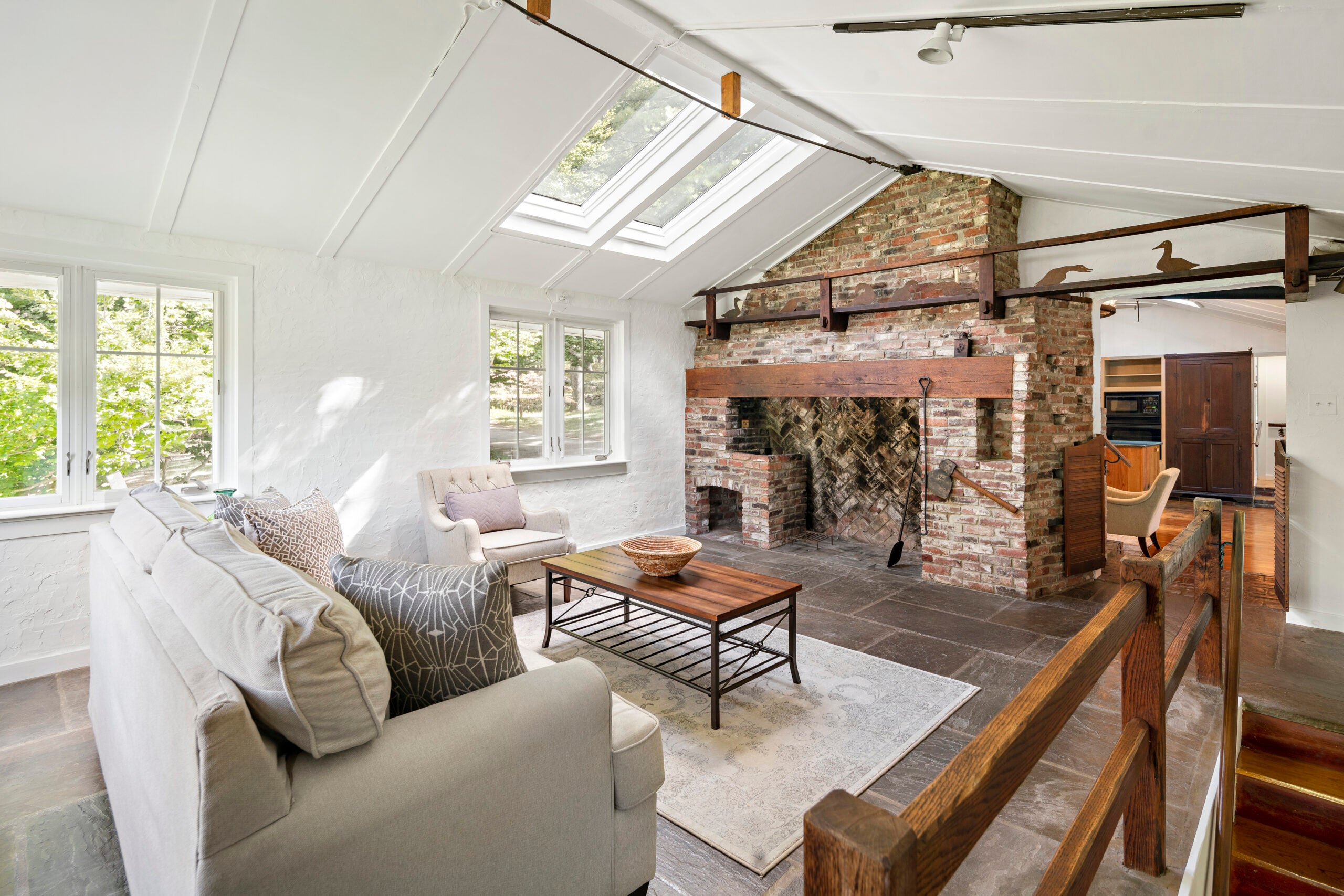 A white-walled room with skylights and  a brick fireplace.