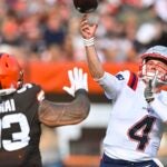 New England Patriots quarterback Bailey Zappe (4) throws a touchdown pass to tight end Hunter Henry (not shown) over Cleveland Browns defensive tackle Tommy Togiai (93), Sunday, Oct. 16, 2022, in Cleveland.