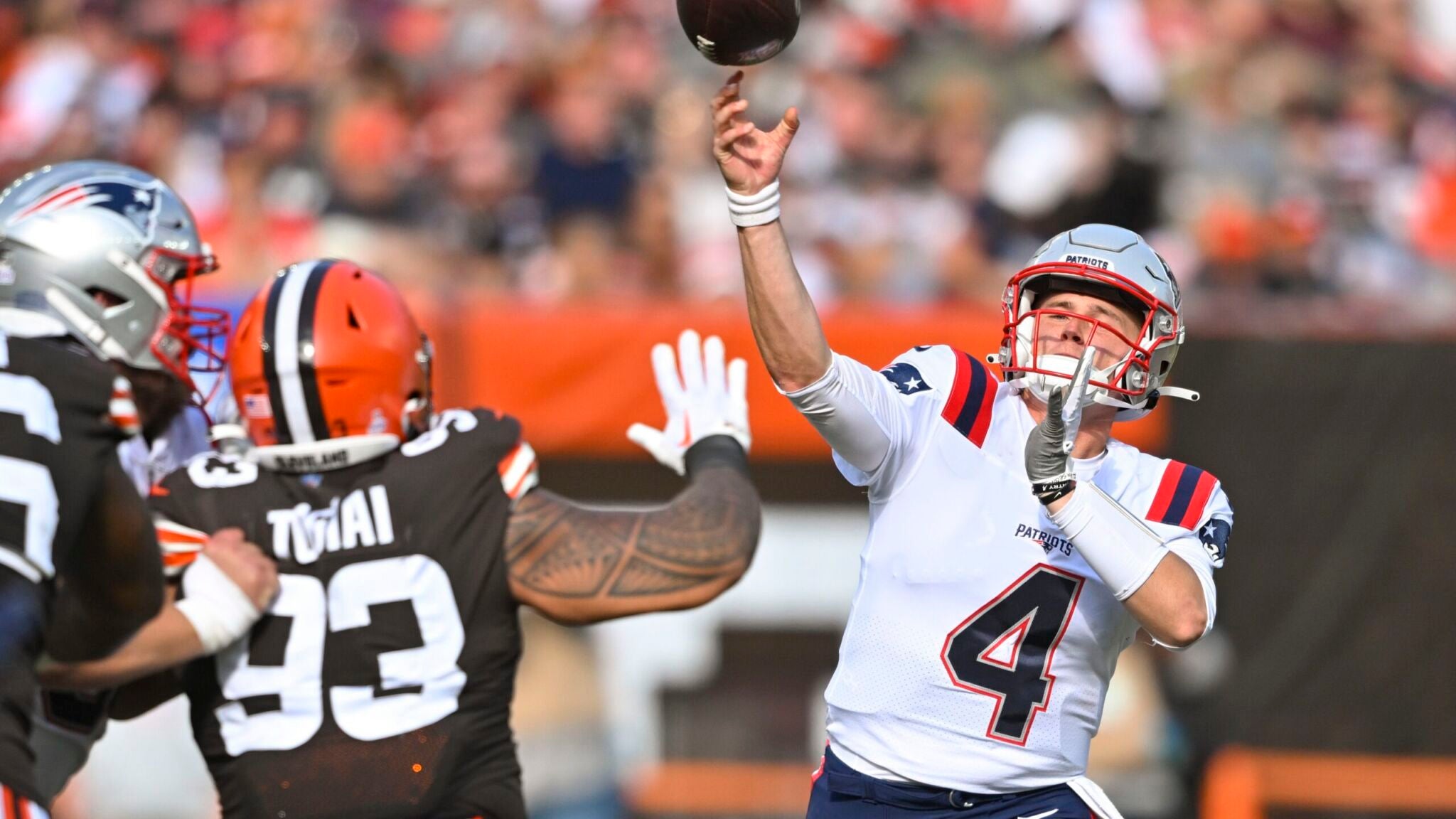 New England Patriots quarterback Bailey Zappe (4) throws a touchdown pass to tight end Hunter Henry (not shown) over Cleveland Browns defensive tackle Tommy Togiai (93), Sunday, Oct. 16, 2022, in Cleveland.