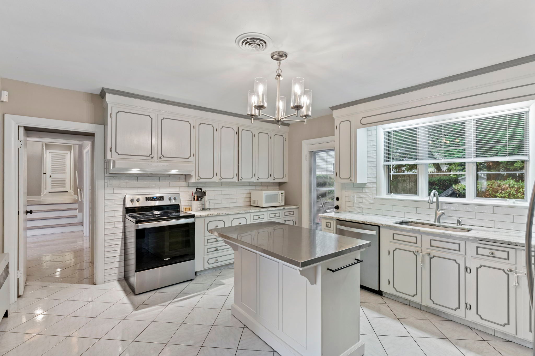 Beige walls, white kitchen with honed-frame cabinetry and tile flooring.