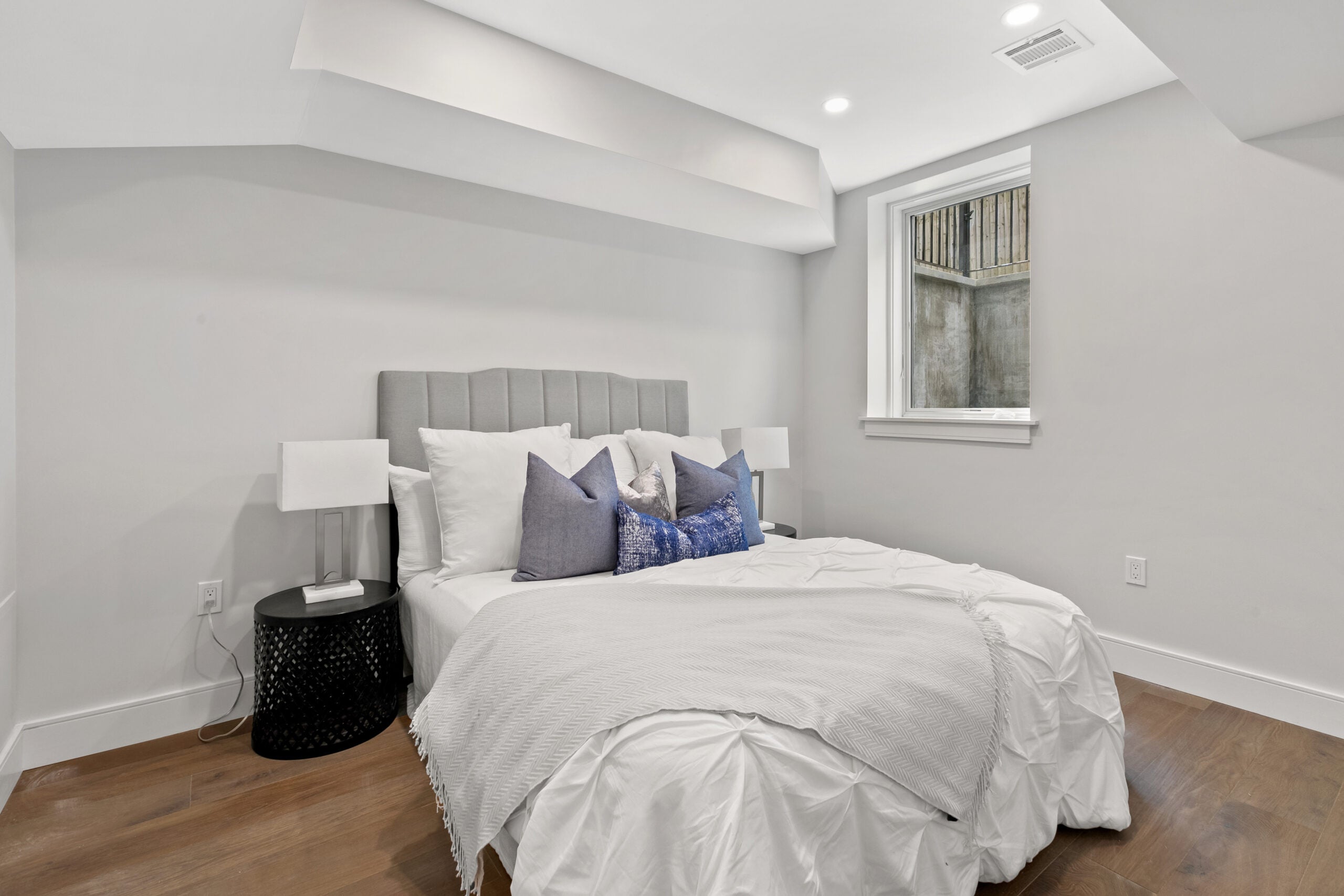The bottom floor bedroom with a window, recessed lighting and a bed in the center of the room at 154 Thorndike.