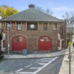 The exterior of a brick fireplace with two bright red fire doors.
