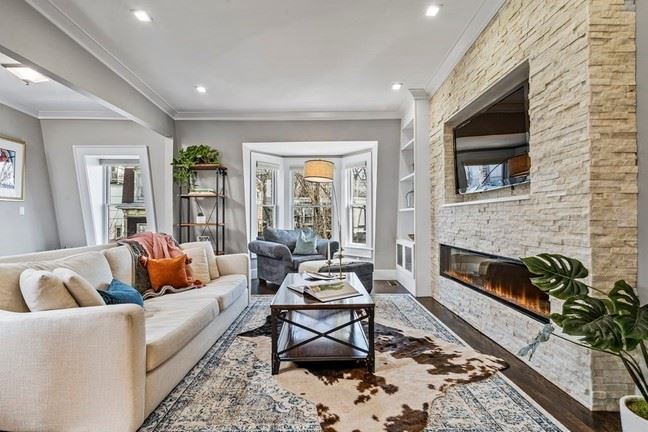 27 Mercer Street Living room with a stone surrounded fireplace in front of seating and window letting in ample light. 
