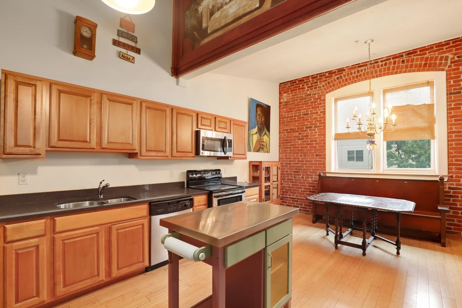 A kitchen with a mural above it and wood flooring and cabinetry.