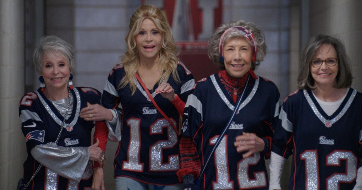 (L to R) Rita Moreno, Jane Fonda, Lily Tomlin, and Sally Field walk through a stadium tunnel wearing Patriots jerseys in '80 For Brady,' the upcoming Tom Brady movie.