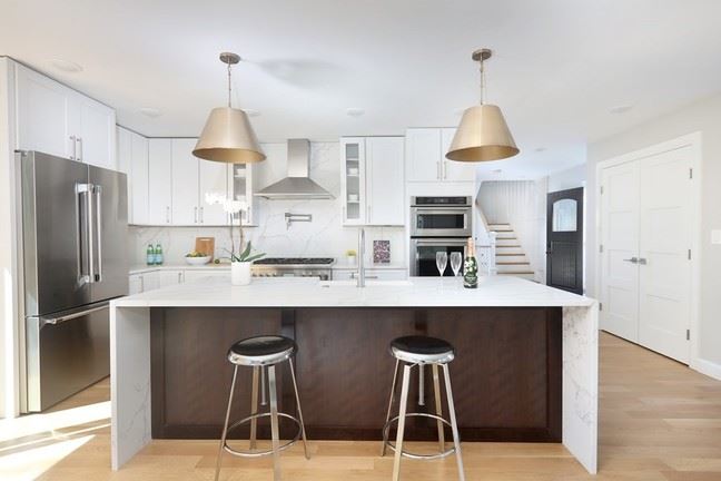 90 Holworthy St Cambridge Kitchen with brass lights atop a waterfall island and stainless steel appliances. 