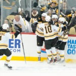 Bruins players celebrate after scoring the game winning goal against the Pittsburgh Penguins in overtime.