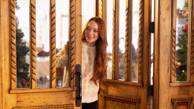 Lindsay Lohan enters a room wearing a white sweater in the Netflix holiday movie "Falling For Christmas."
