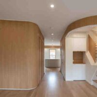A view of curvy wood-clad and white walls into the kitchen. The room is unfurnished.