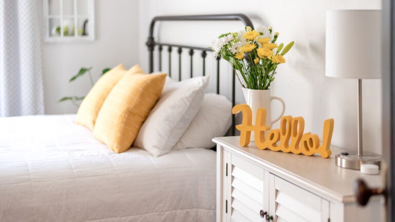 Cheerful yellow hello sign and fresh flowers in a clean and bright bedroom