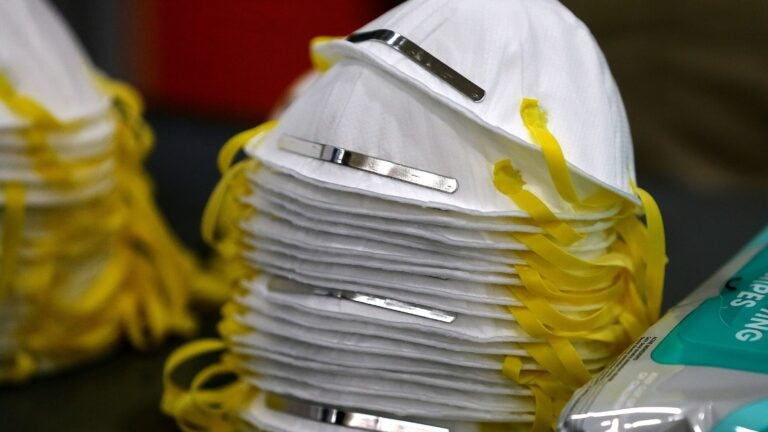 alt = stack of white N-95 masks with yellow elastics