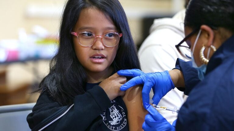 A 3rd grader gets her COVID-19 booster shot at a vaccination clinic where flu shots were also offered.