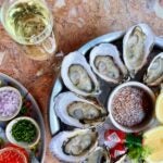 Trays of oysters and mignonette with a glass of champagne at Oak Long Bar