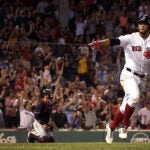 Xander Bogaerts pointing to the Red Sox dugout as he begins rounding the bases on a home run.