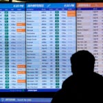 A traveler reads a flight board Tuesday in Terminal C at Boston Logan International Airport.
