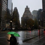 A pedestrian protects himself from rain in Post Office Square in Boston.