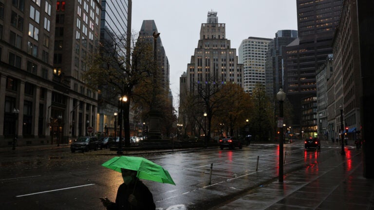 A pedestrian protects himself from rain in Post Office Square in Boston.