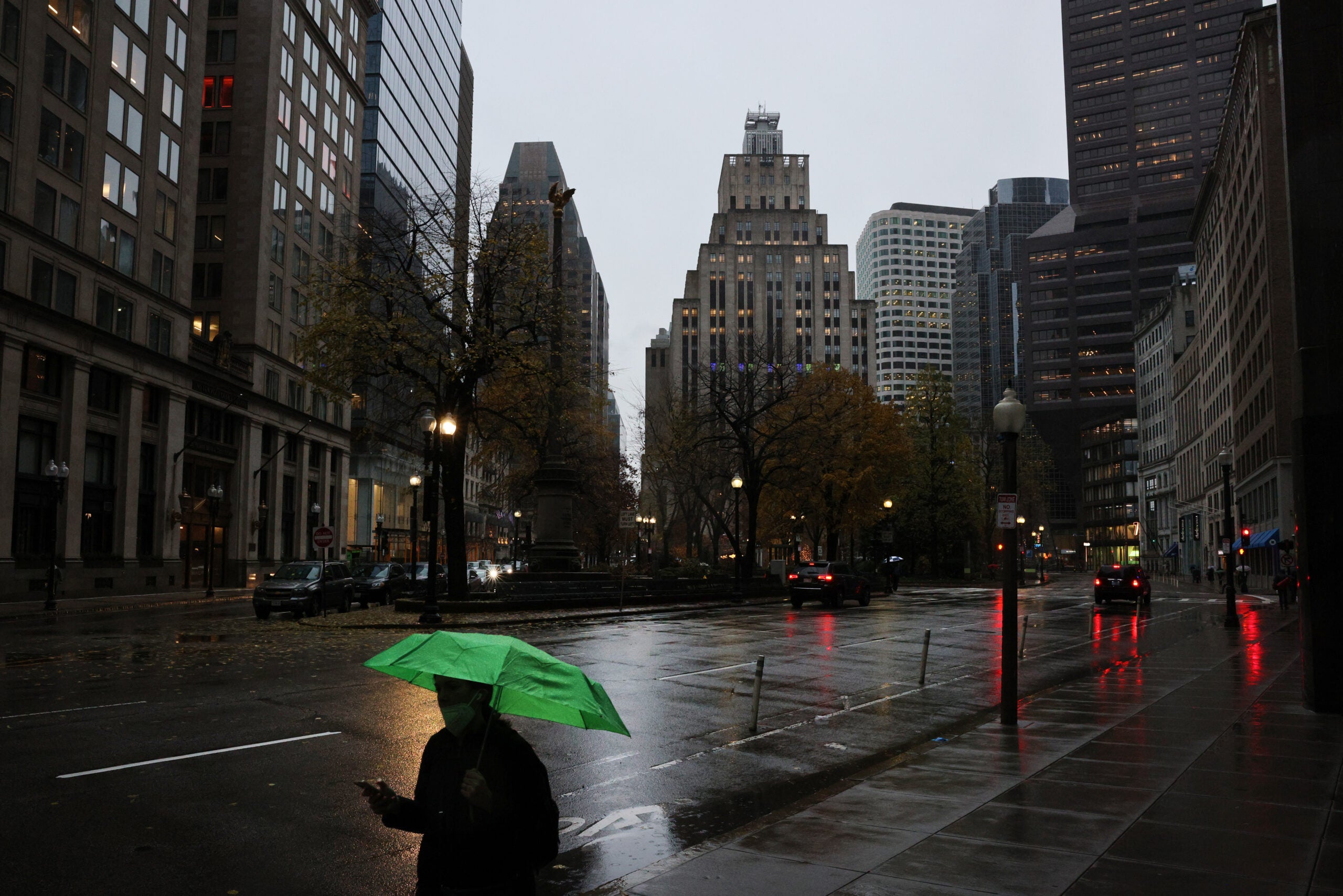 A pedestrian protects himself from rain in Post Office Square in Boston.