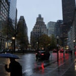 Boston weather: A pedestrian protects himself from the early morning rain in Post Office Square