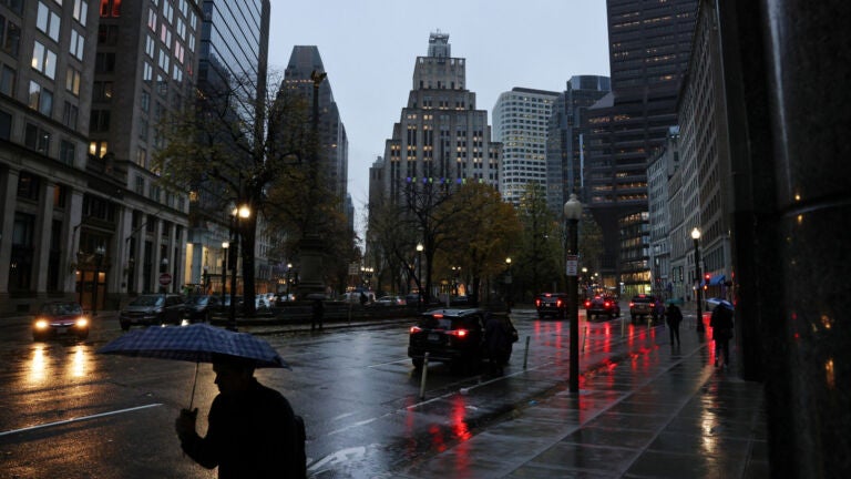 Boston weather: A pedestrian protects himself from the early morning rain in Post Office Square