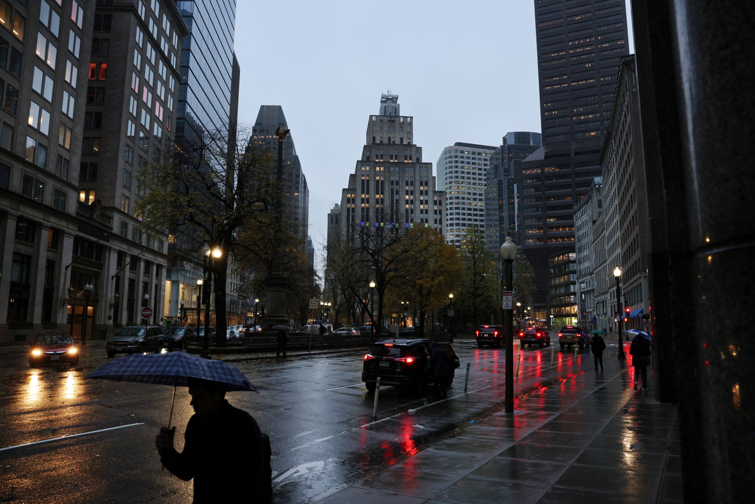 Boston weather: A pedestrian protects himself from the early morning rain in Post Office Square