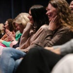 alt = audience members laugh while listening to Elin Hilderbrand speak at the White Heron Theatre in Nantucket, Mass.