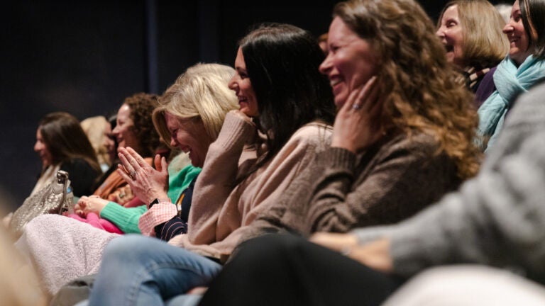 alt = audience members laugh while listening to Elin Hilderbrand speak at the White Heron Theatre in Nantucket, Mass.