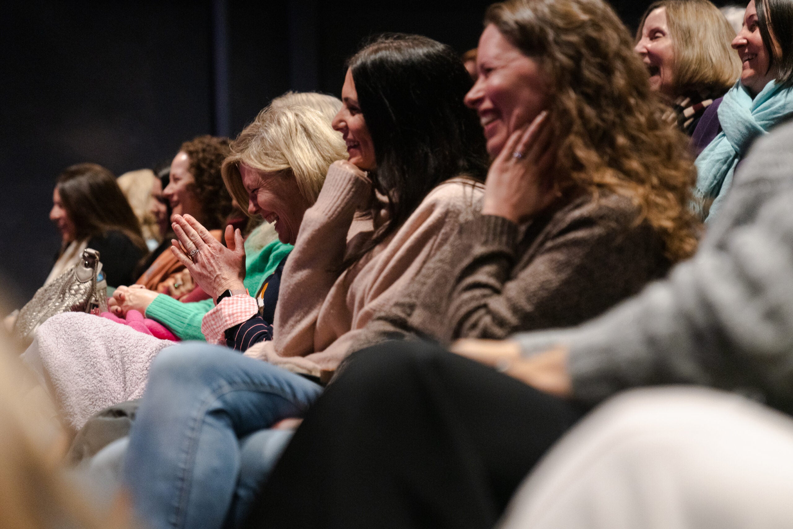 alt = audience members laugh while listening to Elin Hilderbrand speak at the White Heron Theatre in Nantucket, Mass.