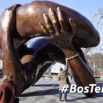 A man reaches to touch a detail of the 20-foot-high bronze sculpture "The Embrace," a memorial to Dr. Martin Luther King Jr. and Coretta Scott King, in the Boston Common, Tuesday, Jan. 10, 2023, in Boston. The sculpture, consisting of four intertwined arms, was inspired by a photo of the Kings embracing when MLK learned he had won the Nobel Peace Prize in 1964. The statue is to be unveiled during ceremonies Friday, Jan. 13, 2023.