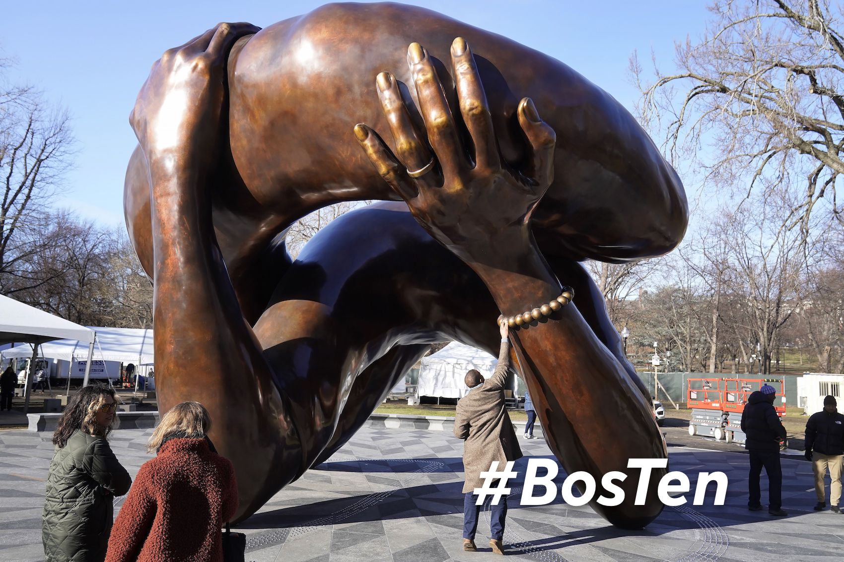 A man reaches to touch a detail of the 20-foot-high bronze sculpture "The Embrace," a memorial to Dr. Martin Luther King Jr. and Coretta Scott King, in the Boston Common, Tuesday, Jan. 10, 2023, in Boston. The sculpture, consisting of four intertwined arms, was inspired by a photo of the Kings embracing when MLK learned he had won the Nobel Peace Prize in 1964. The statue is to be unveiled during ceremonies Friday, Jan. 13, 2023.