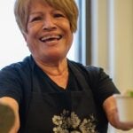 A smiling vendor serves cups of pozole at the Bowl of 'Zole festival in Boston