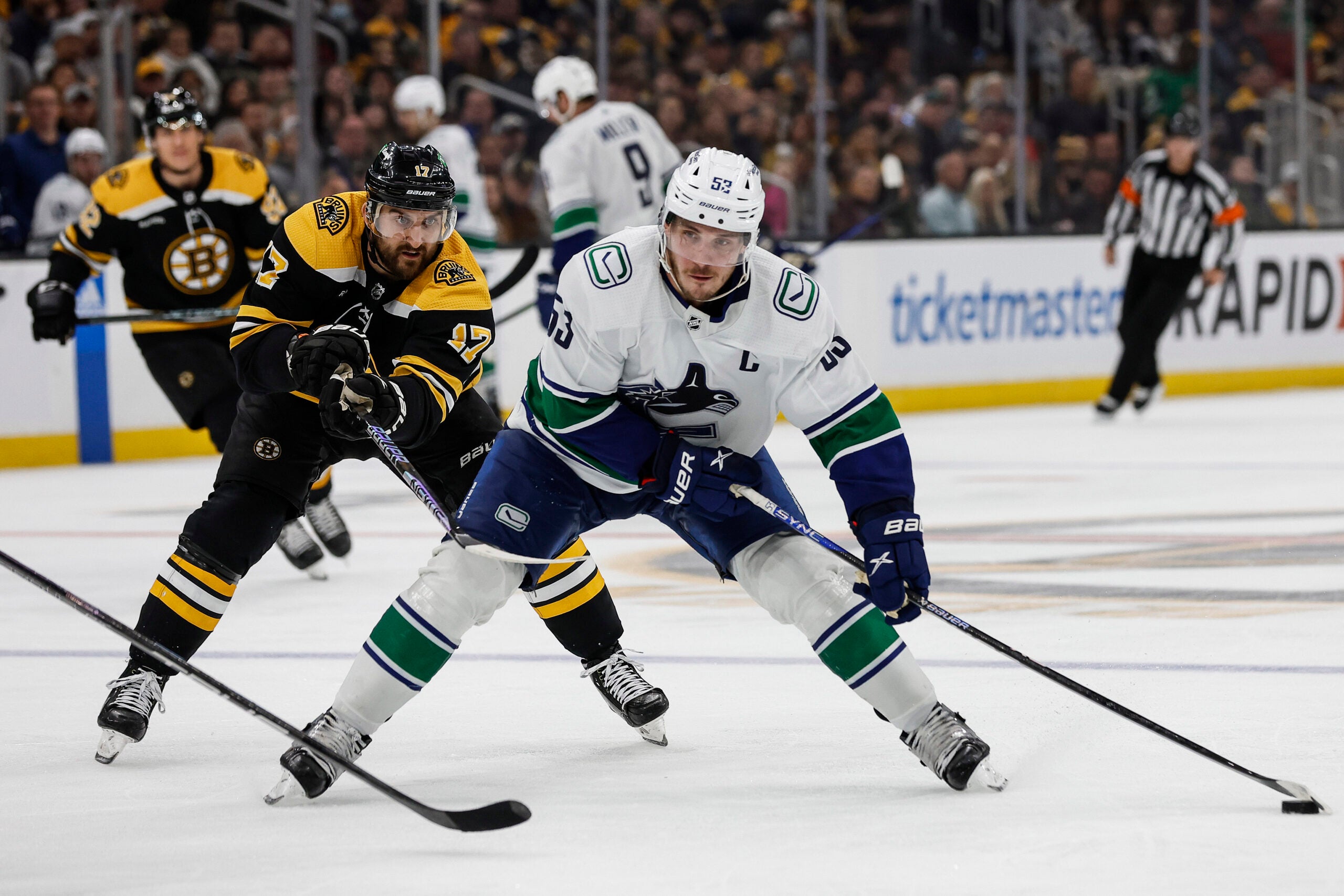 Boston Bruins' Nick Foligno (17) tries to slow down Vancouver Canucks' Bo Horvat during the third period of an NHL hockey game Sunday, Nov. 13, 2022, in Boston.