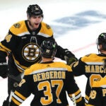 Boston Bruins left wing Jake DeBrusk (74) celebrates his 2nd period goal to tie the game, 2-2, as he is congratulated by Boston Bruins center Patrice Bergeron (37), Boston Bruins left wing Brad Marchand (63) and Boston Bruins right wing David Pastrnak (88).