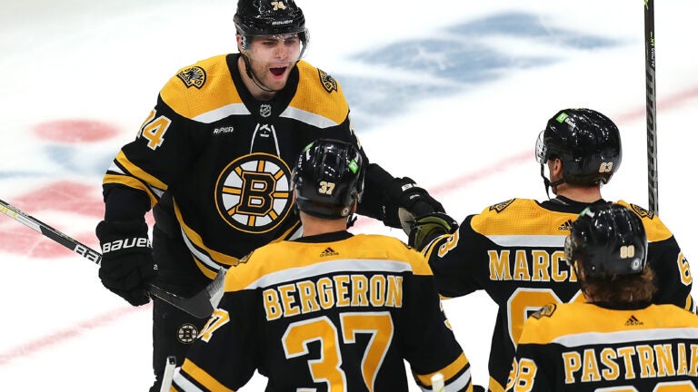 Boston Bruins left wing Jake DeBrusk (74) celebrates his 2nd period goal to tie the game, 2-2, as he is congratulated by Boston Bruins center Patrice Bergeron (37), Boston Bruins left wing Brad Marchand (63) and Boston Bruins right wing David Pastrnak (88).