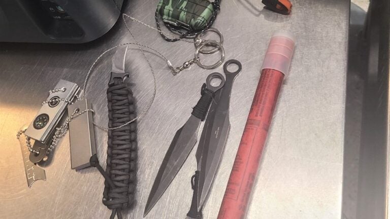 alt = The TSA confiscated a flare, three throwing knives, a torch lighter, two magnesium fire starters, and a paracord tactical knife bracelet all from one passenger's carry-on bag at Boston Logan Airport on Dec. 5, 2022.